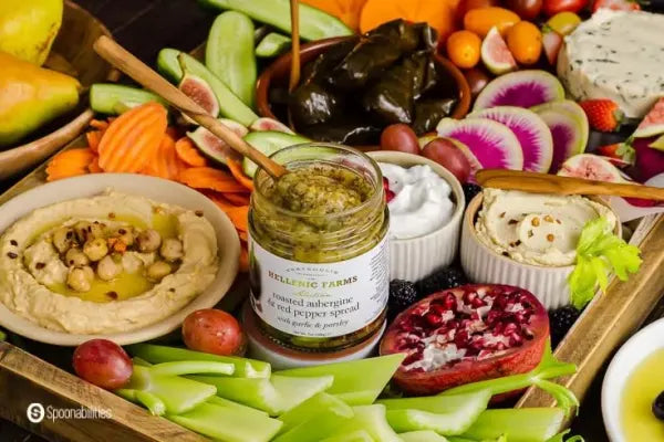 Assorted fruits, vegetables, and a jar of EGGPLANT & RED PEPPER SPREAD
 on a wooden board.